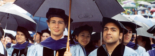 Doctor of Law graduates sit under umbrellas at the 2004 Commencement ceremony.